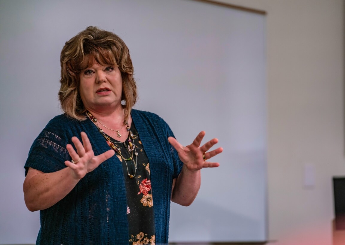 A woman presents at the front of a classroom