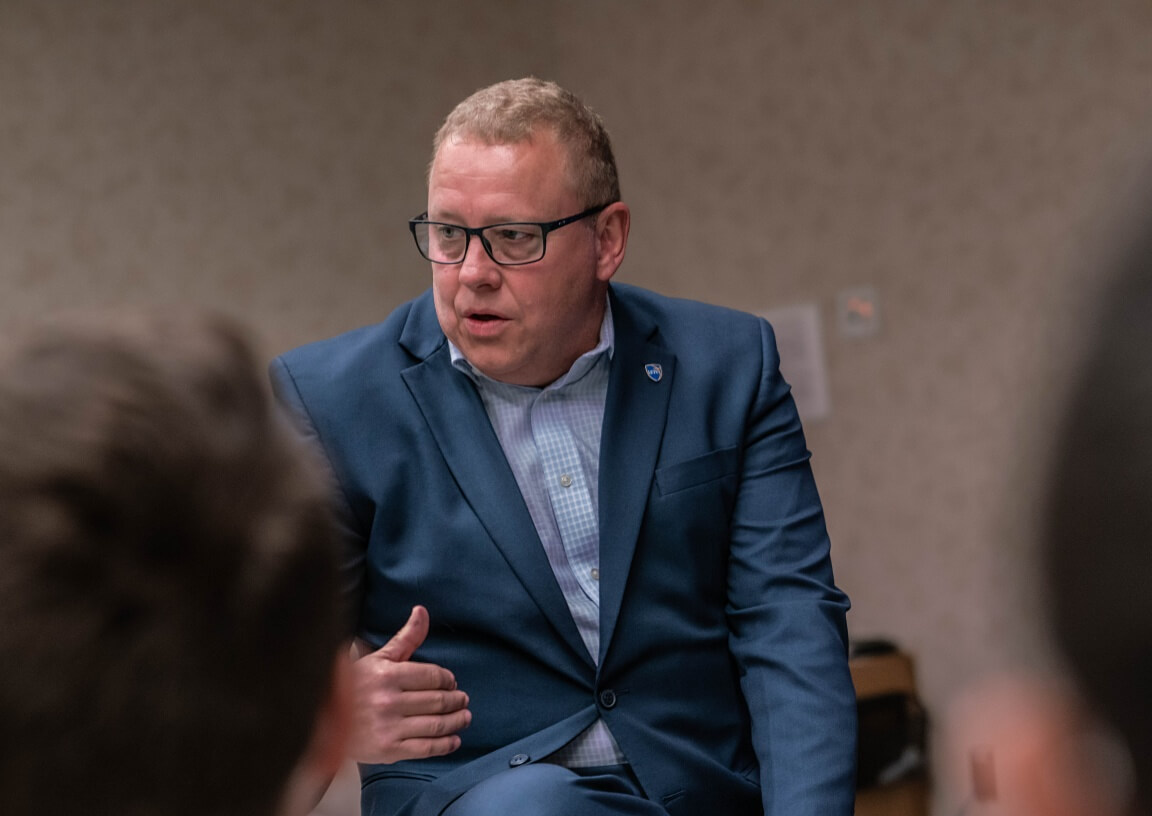 A man talks with students at a table